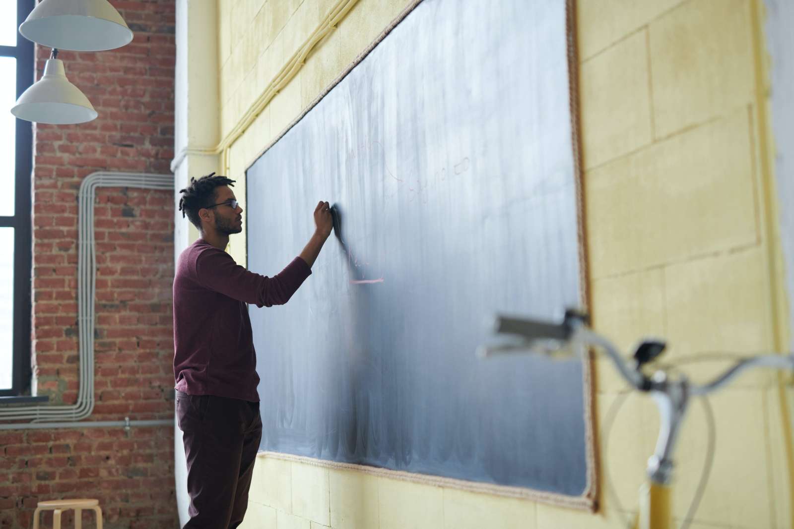 A person writing on a chalkboard in a classroom.